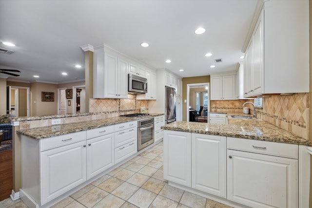 kitchen with white cabinetry, light stone counters, appliances with stainless steel finishes, and kitchen peninsula