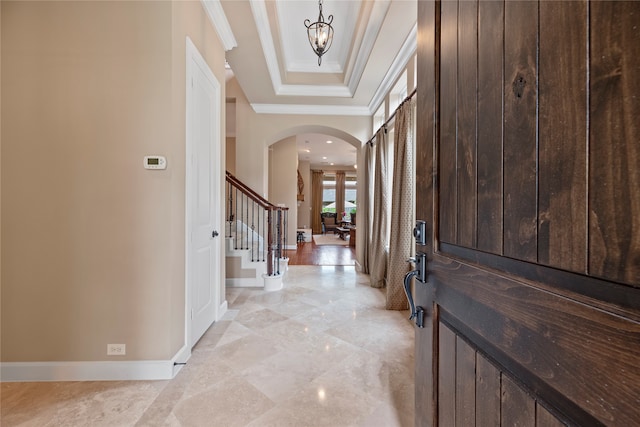 foyer entrance with crown molding and a notable chandelier