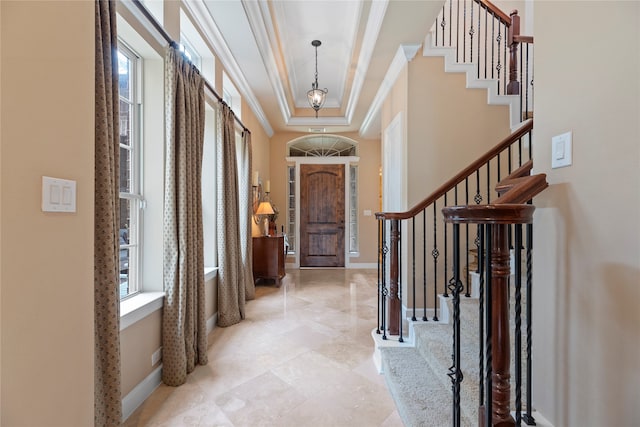 entryway with ornamental molding, a tray ceiling, and plenty of natural light