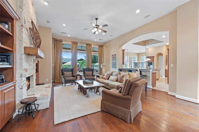 living room with ceiling fan, wood-type flooring, and a fireplace