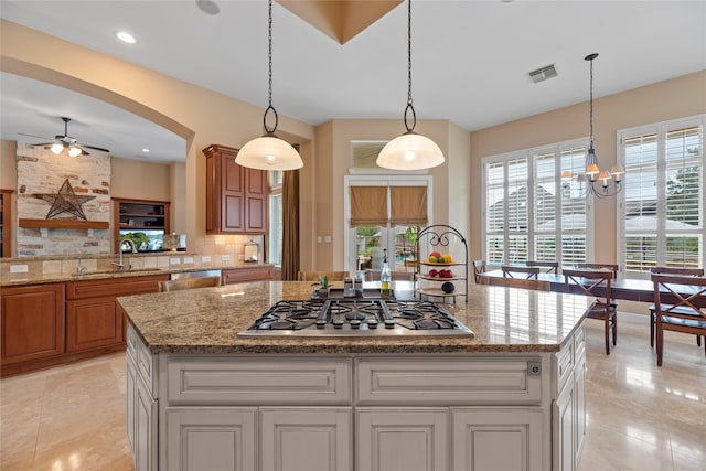 kitchen with decorative backsplash, a kitchen island, appliances with stainless steel finishes, decorative light fixtures, and sink