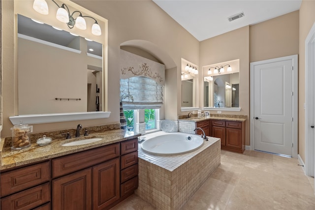 bathroom featuring vanity, tile patterned flooring, and tiled tub