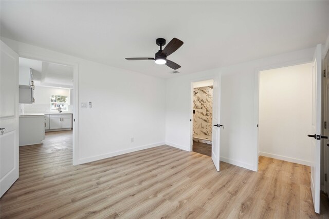 unfurnished bedroom with light hardwood / wood-style flooring, ensuite bathroom, and ceiling fan