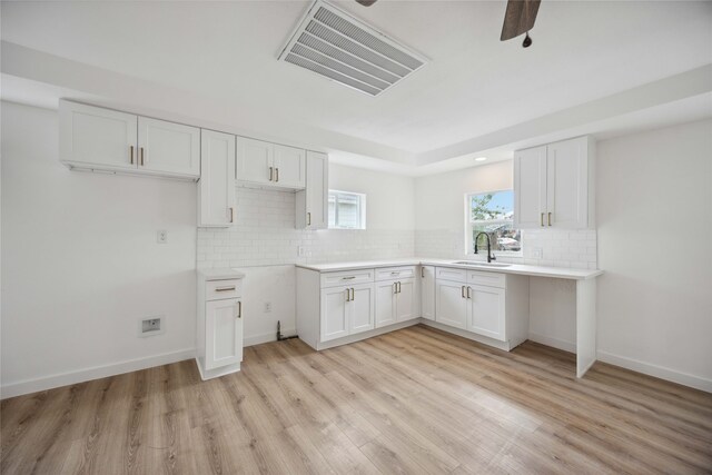 kitchen featuring sink, white cabinets, decorative backsplash, and light wood-type flooring