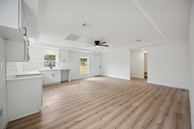 unfurnished living room with light hardwood / wood-style floors, sink, and ceiling fan