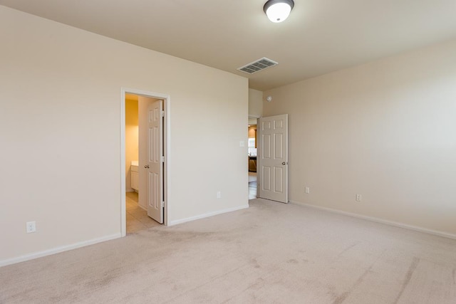 unfurnished bedroom with ensuite bathroom and light colored carpet