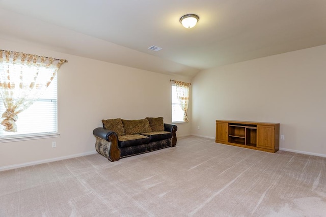 living area featuring lofted ceiling, light carpet, and a healthy amount of sunlight