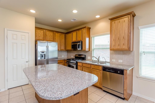 kitchen featuring sink, a kitchen island, stainless steel appliances, and tasteful backsplash