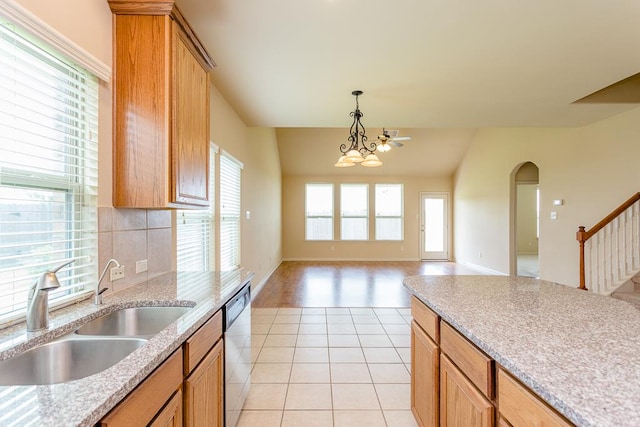 kitchen with sink, vaulted ceiling, stainless steel dishwasher, decorative light fixtures, and light hardwood / wood-style flooring