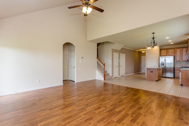 kitchen featuring stainless steel fridge, a kitchen island, ceiling fan with notable chandelier, light hardwood / wood-style floors, and decorative light fixtures