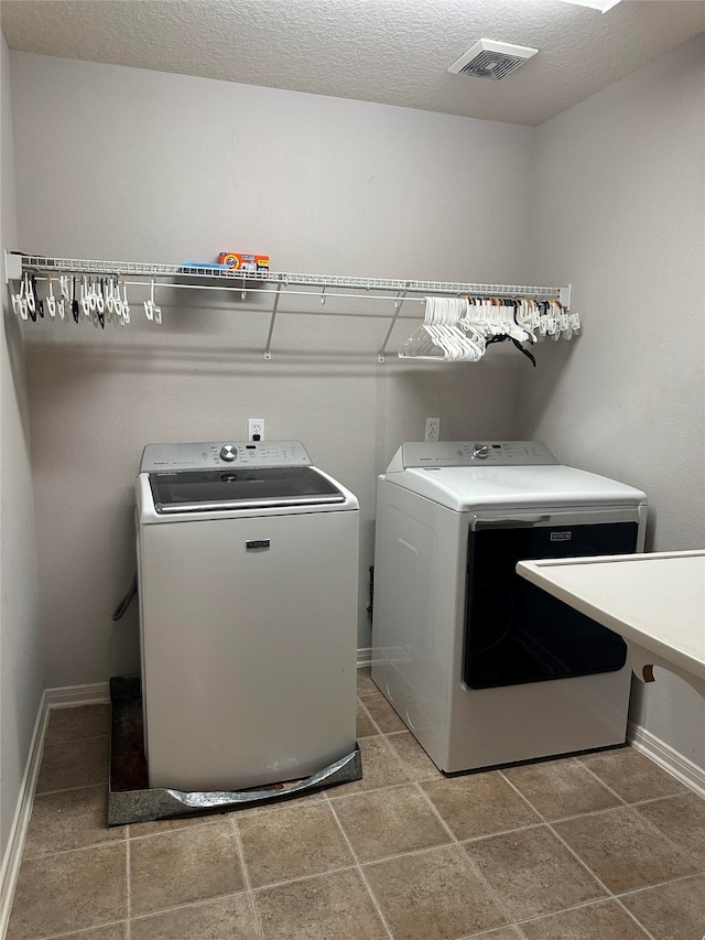 laundry area with washing machine and clothes dryer and a textured ceiling