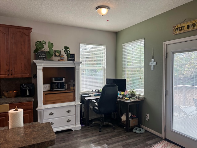 office with a textured ceiling, dark wood-type flooring, and a healthy amount of sunlight