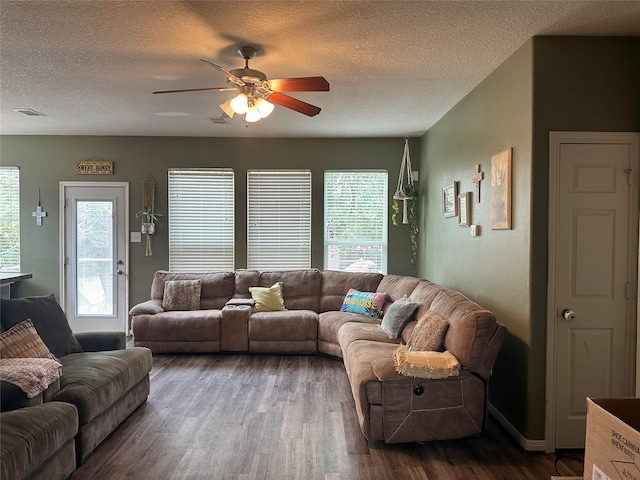 living room with a textured ceiling, ceiling fan, and dark wood-type flooring