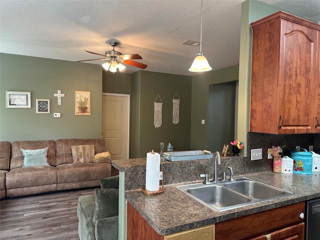 kitchen featuring sink, dark hardwood / wood-style flooring, backsplash, pendant lighting, and a textured ceiling