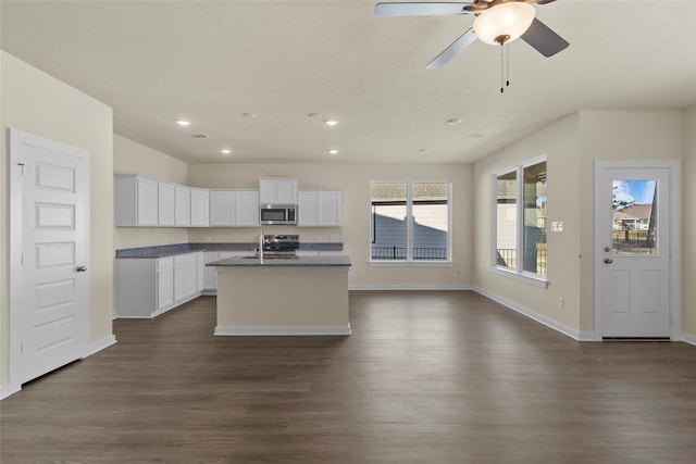 kitchen featuring dark wood-type flooring, white cabinets, an island with sink, a wealth of natural light, and stainless steel appliances