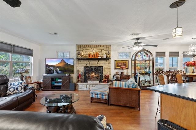 living room with a textured ceiling, ceiling fan with notable chandelier, a fireplace, and hardwood / wood-style flooring