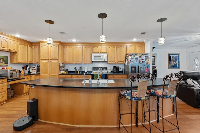 kitchen with a center island with sink, sink, light hardwood / wood-style flooring, and appliances with stainless steel finishes