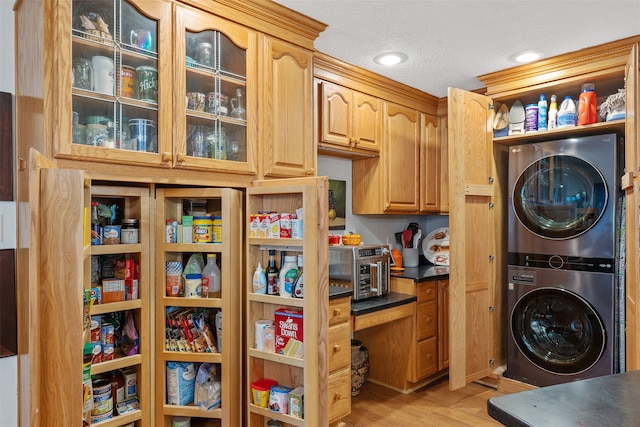 laundry area with stacked washer and clothes dryer, a textured ceiling, and light wood-type flooring