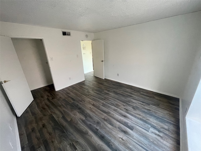 unfurnished bedroom with a textured ceiling and dark hardwood / wood-style floors