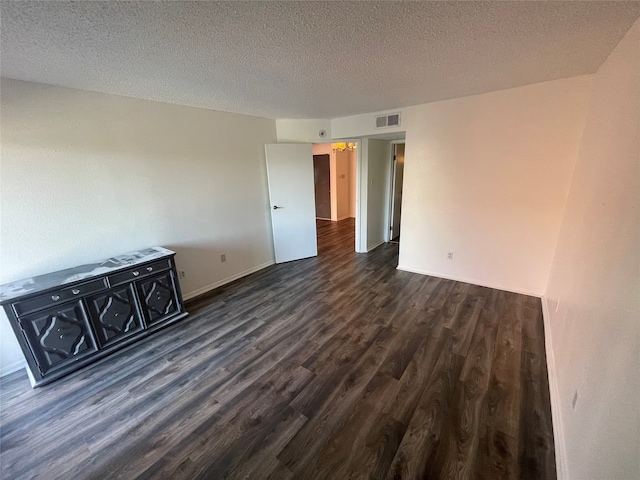 empty room with dark wood-type flooring and a textured ceiling