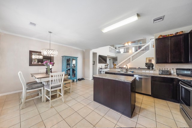 kitchen with light stone countertops, appliances with stainless steel finishes, hanging light fixtures, and dark brown cabinets