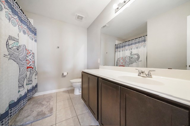 bathroom with toilet, vanity, and tile patterned flooring