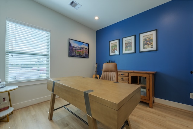 home office with light wood-type flooring and a healthy amount of sunlight