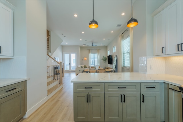 kitchen featuring light stone countertops, french doors, hanging light fixtures, light wood-type flooring, and decorative backsplash