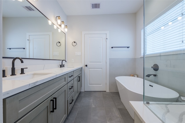 bathroom featuring a bathing tub, vanity, and tile patterned floors