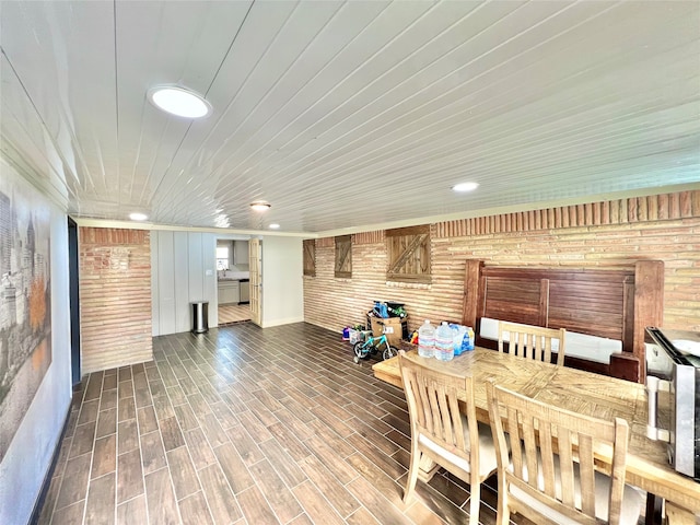 dining space featuring brick wall, wood-type flooring, and wood ceiling