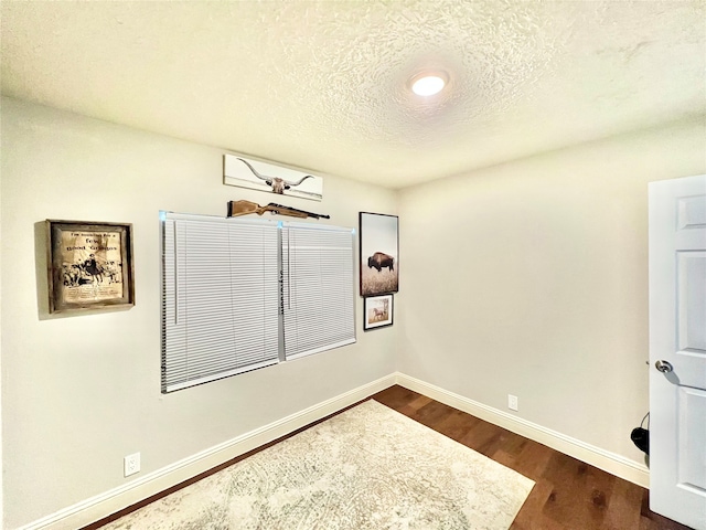 unfurnished room featuring a textured ceiling and dark wood-type flooring