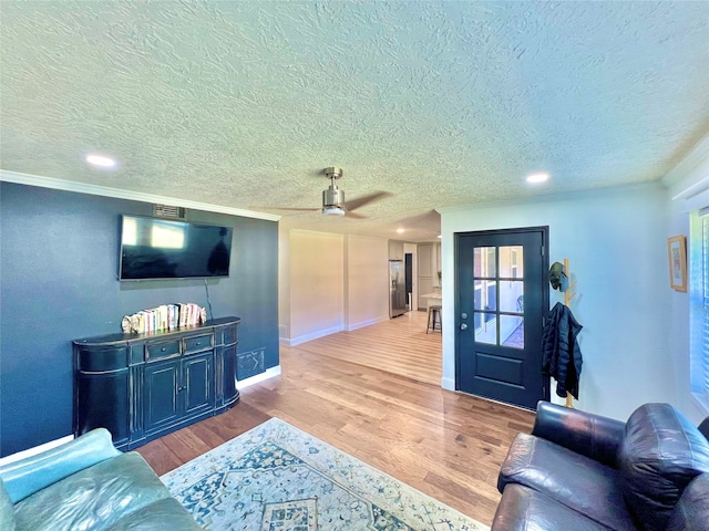 living room featuring light hardwood / wood-style floors, a textured ceiling, and ceiling fan