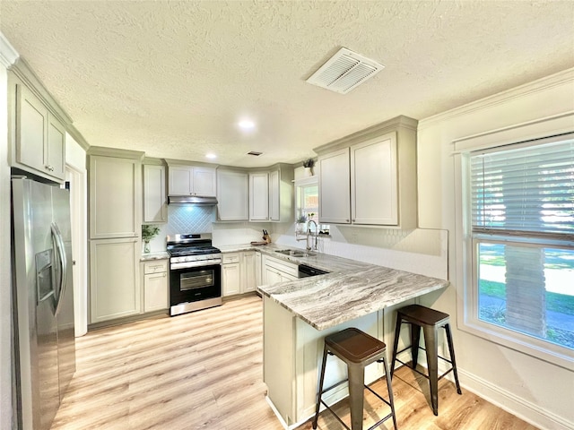 kitchen featuring a breakfast bar, stainless steel appliances, a wealth of natural light, and kitchen peninsula