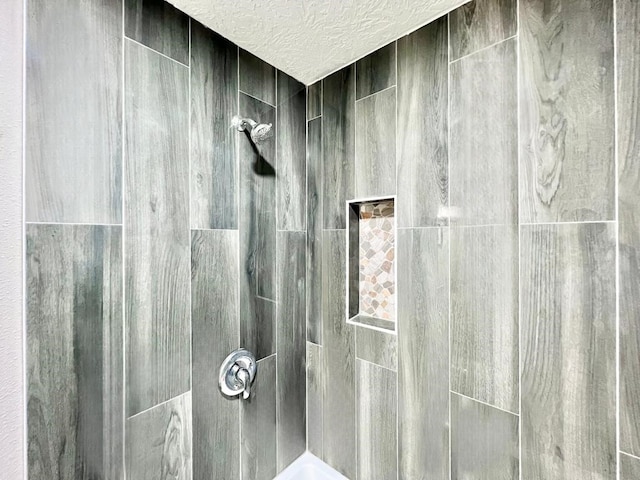 room details featuring a textured ceiling and tiled shower