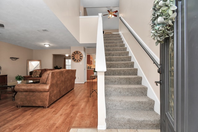 stairway with hardwood / wood-style flooring and ceiling fan