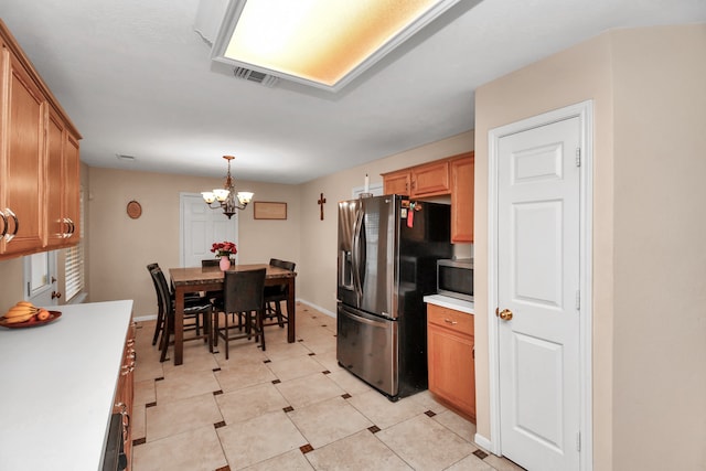 kitchen featuring pendant lighting, stainless steel appliances, light tile patterned floors, and a notable chandelier