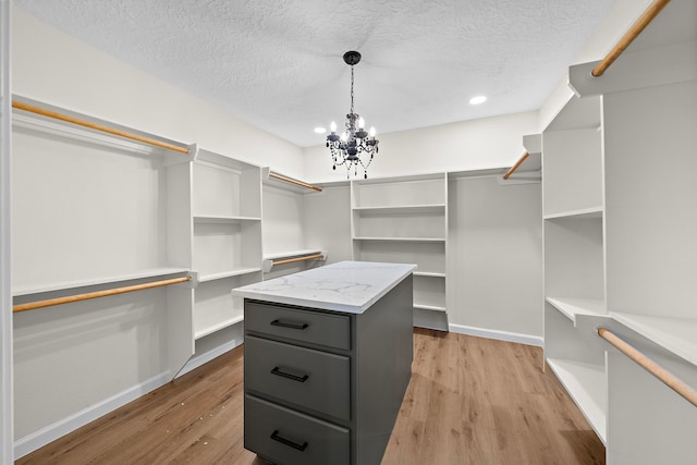 spacious closet featuring a notable chandelier and light wood-type flooring