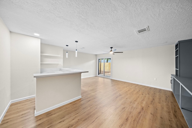 unfurnished living room featuring ceiling fan, a textured ceiling, and light wood-type flooring