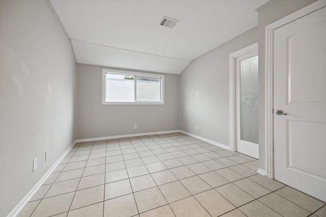 tiled empty room featuring vaulted ceiling