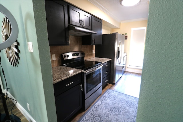 kitchen with backsplash, appliances with stainless steel finishes, light wood-type flooring, crown molding, and light stone counters