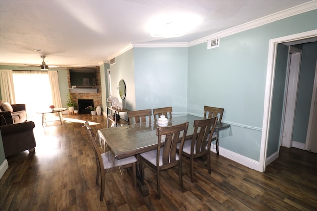 dining room with crown molding, a stone fireplace, dark hardwood / wood-style floors, and ceiling fan