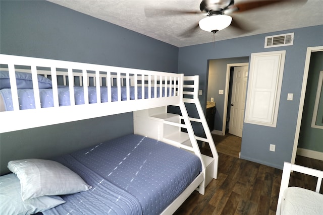 bedroom with ceiling fan, a textured ceiling, and dark hardwood / wood-style flooring