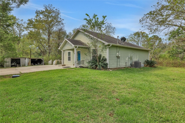 view of front of property featuring a front yard, an outbuilding, and central AC unit