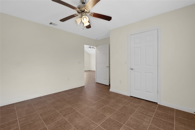 unfurnished bedroom with dark tile patterned flooring and ceiling fan