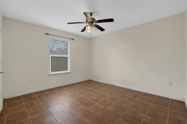 unfurnished room featuring dark tile patterned flooring and ceiling fan