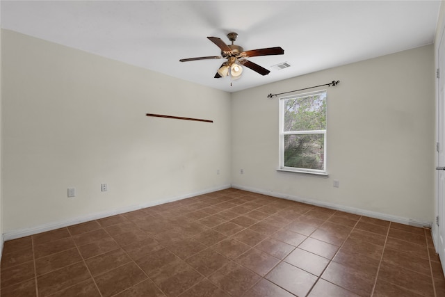 spare room with dark tile patterned floors and ceiling fan