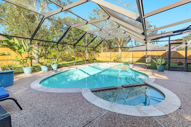 view of pool with a patio area, an in ground hot tub, and glass enclosure