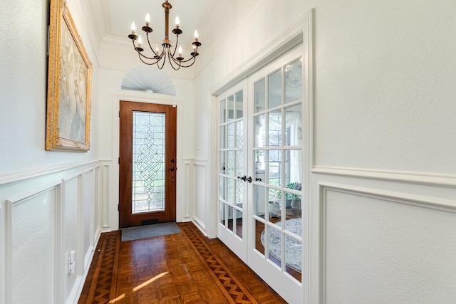 doorway featuring dark parquet flooring, french doors, a chandelier, and ornamental molding