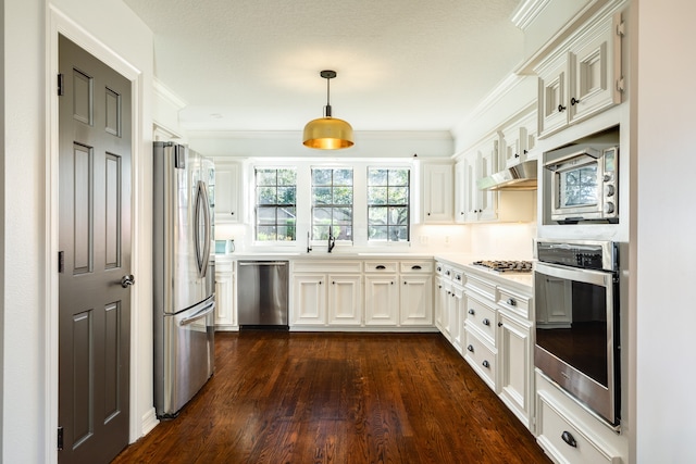 kitchen featuring appliances with stainless steel finishes, crown molding, white cabinets, dark hardwood / wood-style floors, and hanging light fixtures