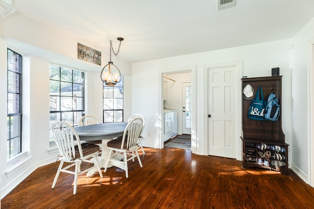 dining area with dark hardwood / wood-style floors, washing machine and dryer, and an inviting chandelier